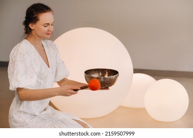 Portrait Of A Female Yoga Teacher Playing A Tibetan Bowl Or Singing A Bell In The Gym During A Yoga Retreat.