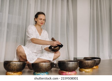 Portrait Of A Female Yoga Teacher Playing A Tibetan Bowl Or Singing A Bell In The Gym During A Yoga Retreat.