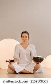 Portrait Of A Female Yoga Teacher Playing A Tibetan Bowl Or Singing A Bell In The Gym During A Yoga Retreat.