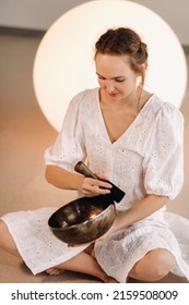 Portrait Of A Female Yoga Teacher Playing A Tibetan Bowl Or Singing A Bell In The Gym During A Yoga Retreat.