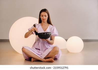 Portrait Of A Female Yoga Teacher Playing A Tibetan Bowl Or Singing A Bell In The Gym During A Yoga Retreat.