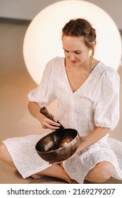 Portrait Of A Female Yoga Teacher Playing A Tibetan Bowl Or Singing A Bell In The Gym During A Yoga Retreat.