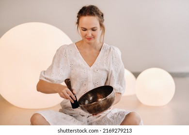 Portrait Of A Female Yoga Teacher Playing A Tibetan Bowl Or Singing A Bell In The Gym During A Yoga Retreat.