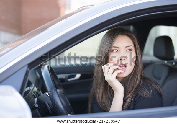 Portrait of female Young adult brunette dreaming\
and looking far away girl sitting in luxury black car Slim cute\
asian scary woman listening music inside black leather chair auto \
Fingers on forehead