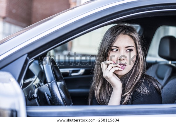 Portrait of female Young adult dreaming and looking\
far away girl sitting in luxury black car Slim cute asian scary\
woman listening music inside black leather chair auto hand Fingers\
caress big lips