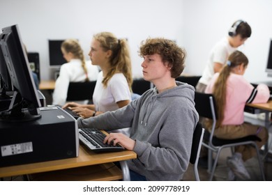 Portrait of a fifteen-year-old schoolboy sitting at a computer in the class at a informatics lesson - Shutterstock ID 2099778919