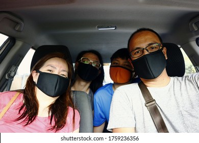 Portrait of a Filipino family with face mask on while inside a car.