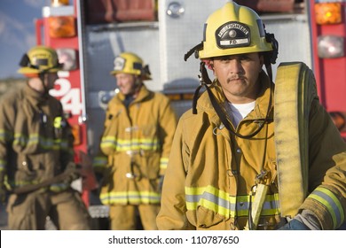 Portrait Of A Fire Fighter Carrying Fire Hose On Shoulder