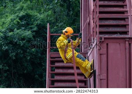 Portrait of firefighter in fireproof clothe rappelling from the burning building full of smoke using rope access for fire extinguish risk rescue mission and accident management usage