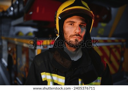 Portrait of a firefighter in a protective suit and a protective helmet standing by a fire engine after working on a fire. Close-up image.
