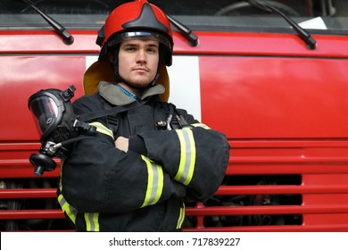Portrait of fireman wearing fire fighter turnouts and red helmet, fold ones arms