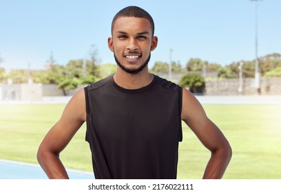 Portrait Of A Fit Active Young Athlete Standing Alone Before Going For A Run On A Track Field. Latino Male Looking Confident And Smiling Outside Getting Ready To Do His Daily Routine Exercise Outside