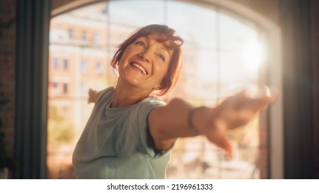 Portrait Of A Fit Middle Aged Woman With A Smile Stretching And Doing Core Strengthening Yoga Exercises During Morning Workout At Home In Bright Apartment. Health And Fitness Concept.