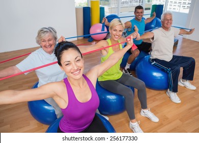 Portrait of fit people on fitness balls exercising with resistance bands in gym - Powered by Shutterstock