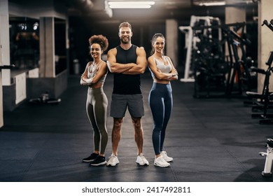 Portrait of fit sporty friends posing in a gym while smiling at the camera. - Powered by Shutterstock