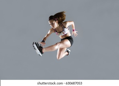 Portrait Of Fit And Sporty Young Woman Jumping On White Background.