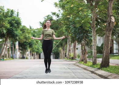 Portrait Of Fit Young Woman With Jump Rope In A Park. Fitness Female Doing Skipping Workout Outdoors