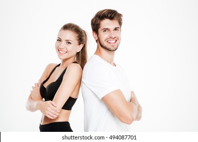 Portrait of a fitness couple standing standing back to back with arms folded isolated on a white background