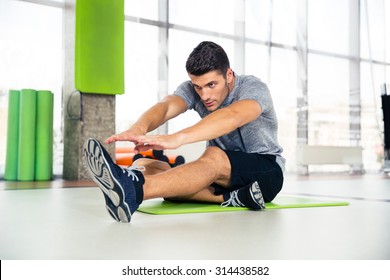 Portrait of a fitness man doing stretching exercises at gym 