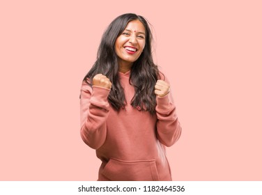 Portrait of fitness young indian woman very happy and excited, raising arms, celebrating a victory or success, winning the lottery