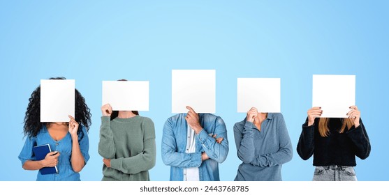 Portrait of five people standing in row over blue background and covering their faces with mock up placards. Concept of teamwork and emotions