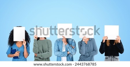 Portrait of five people standing in row over blue background and covering their faces with mock up placards. Concept of teamwork and emotions