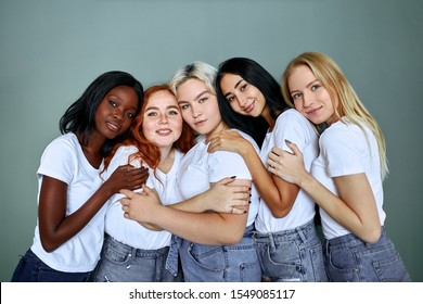 Portrait of five smiling beautiful women in jeans standing together isolated over grey background, hug each other, laugh - Powered by Shutterstock