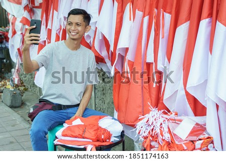 a portrait of a flag seller taking a photo selfie