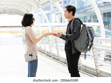 Portrait Fo A Cheerful Young Asian Couple Exchanging Different Books On The City. Person Borrow Textbook, Swap Of Knowledge. Give To Read To A Boyfriend.