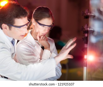 Portrait Of A Focused Electrical Engineering Researchers In Their Working Environment Checking The Phenomenon Of Breaking Laser Beam On The Glass Surface.