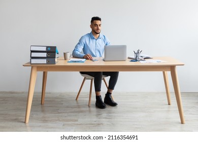 Portrait Of Focused Middle Eastern Male Manager Working On Laptop Computer In Modern Office, Serious Guy Sitting At Desk And Using Pc, Looking At Screen Watching Webinar, Checking Email