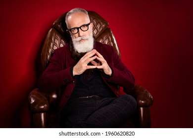 Portrait Of Focused Person Sit In Leather Chair Arms Fingers Together Look Camera Isolated On Dark Red Color Background