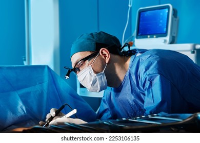 Portrait of focused surgeon wearing protective face mask and headlamp during operation in operating theater of hospital. Profession of surgeon - Powered by Shutterstock