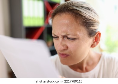 Portrait Of Focused Woman Trying Read Papers, Squinting To See More Clearly. Female Having Difficulties Seeing Text Because Of Vision Problems