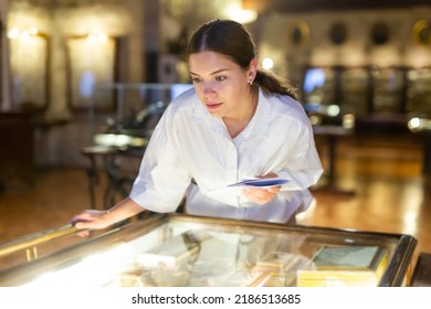 Portrait of focused young girl holding information booklet during visiting exposition of ancient boxes at museum - Shutterstock ID 2186513685