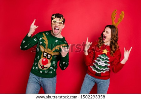 Portrait of foolish two family people wife husband brown hair scream have rock-and-roll show horned sign wear rudolf christmas tree design costume pullover sweater isolated over red color background