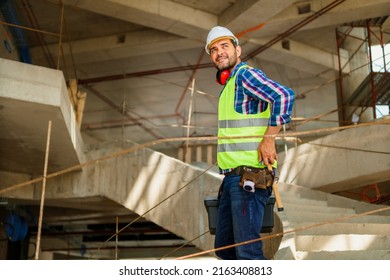 A portrait of a foreman in his 40s who descends the stairs with a tool box on the construction site.