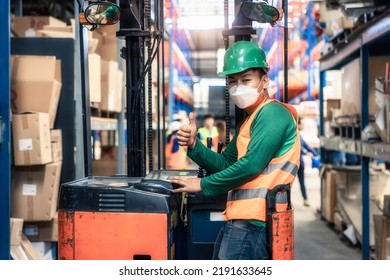 Portrait Of Forklift Operator With Thumb In Distribution Warehouse. May Called Industrial Worker, Driver, Asian Man Or Person. To Wear Safety Helmet, Vest, Mask. Concept For Job, Training, Occupation.