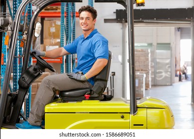 Portrait Of Forklift Truck Driver Smiling At Camera Stacking Boxes In Warehouse