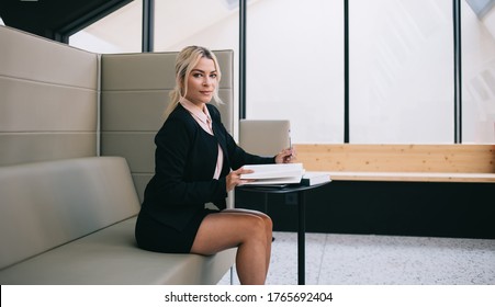 Portrait Of Formally Dressed Female Employee Working In Modern Office Interior Sitting At Table With Education Literature, Attractive 30 Years Old Woman Posing Spending Time For Planning Startup