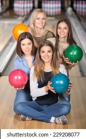 Portrait Of Four Happy Women In Bowling With Colored Balls.