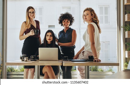 Portrait of four successful young businesswomen together in office. Group of multi-ethnic businesswomen looking at camera.