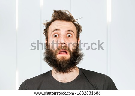 Portrait freak bearded shaggy surprised man with long hair before haircut in barbershop with open mouth and wide eyes.