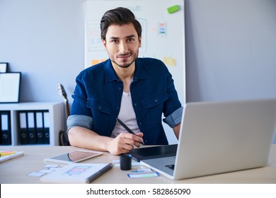 Portrait of freelance graphic designer sitting at desk with laptop and tablet - Powered by Shutterstock