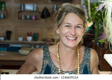 Portrait of french blonde mature woman smiling in her handmade gifts store in France, entrepreneur concept.
