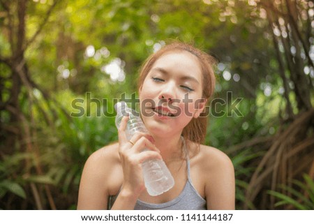Portrait of Fresh Asian woman drinking some water after exercise at park.