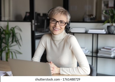 Portrait Of Friendly Call Center Agent Wear Headset With Microphone Working Sit At Desk Smile Look At Camera. Financial Advisor Helpline Specialist Consult Clients Distantly, On-line Tutoring Concept