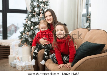 Portrait of friendly family mother and two kids playing, embrace and laugh on Christmas evening. Christmas holiday. Christmas family portrait.