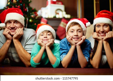 Portrait Of Friendly Family In Santa Caps Looking At Camera On Christmas Evening