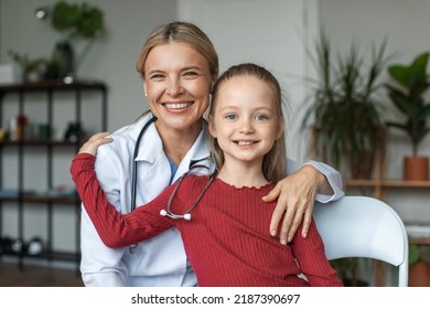 Portrait Of Friendly Nurse In White Coat, Embracing With Happy Little Preschool Patient, Smiling Girl Posing For Photo With Attractive General Practitioner